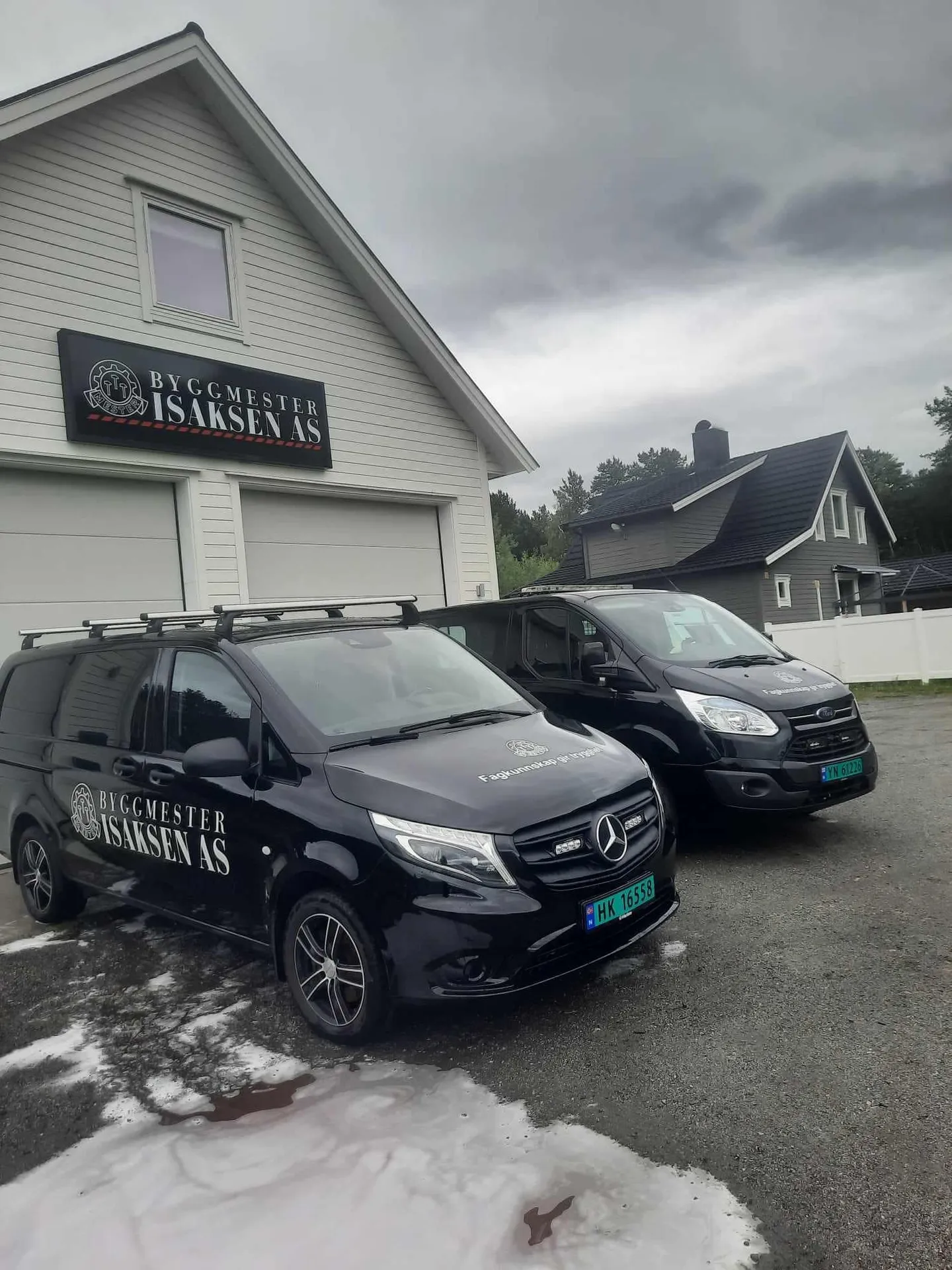 Byggmester Isaksens firmabiler foran verkstedet med firmaskilt